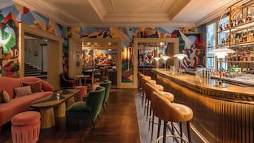 Una zona de bar con mostrador, taburetes y un mural en la pared.