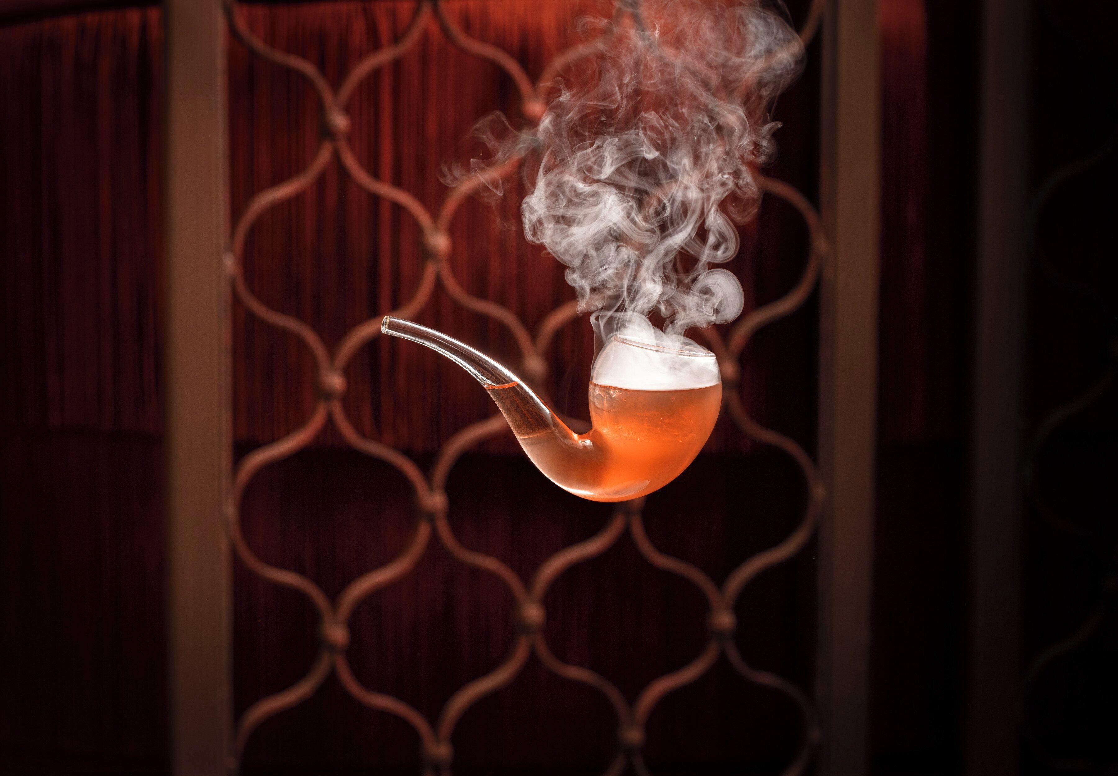 A teapot with steam rising, set against a patterned background.
