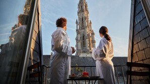 Una pareja en un balcón con vista a una catedral con una aguja alta.