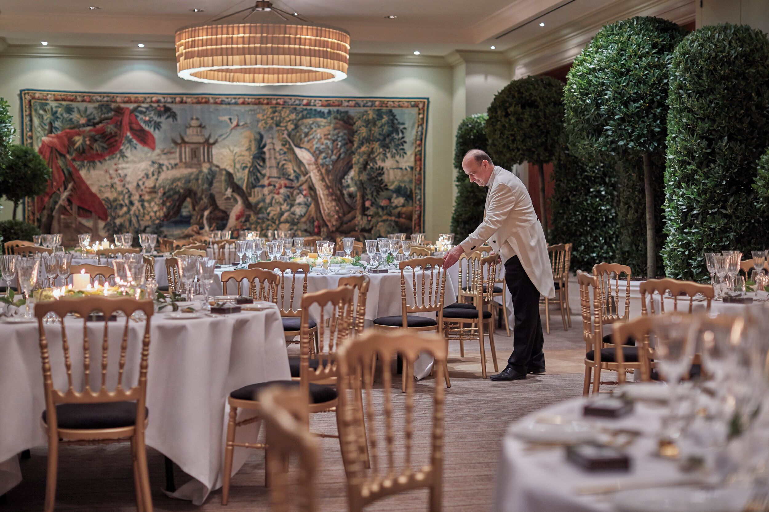 Un comedor formal con mesas redondas, sillas y un cuadro decorativo grande en la pared.