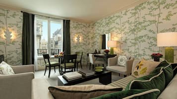 Une chambre d’hôtel comprenant un coin repas, un canapé, une table basse et une vue sur la ville par la fenêtre.