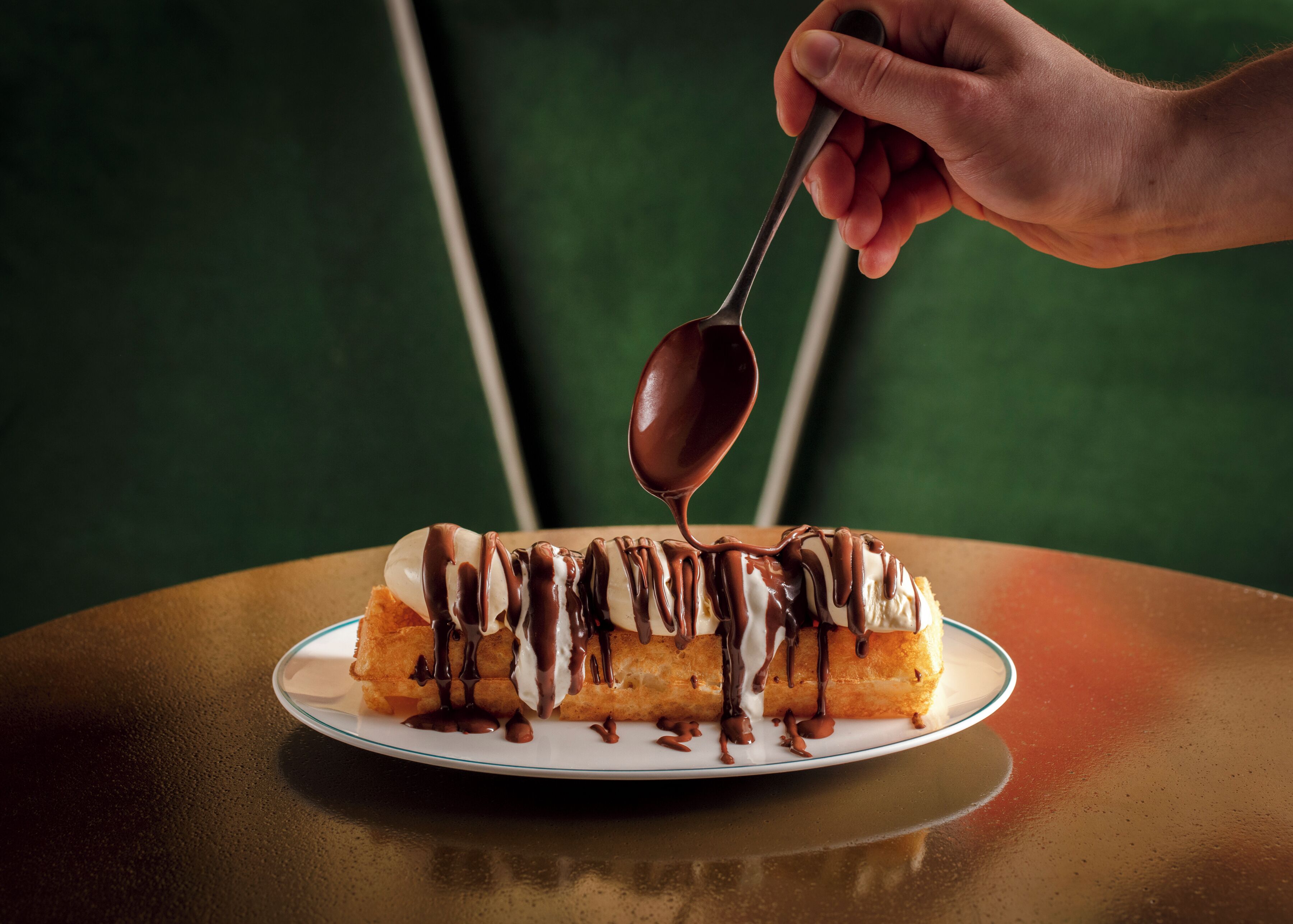 En dessert på en tallrik, och chokladsås hälls över den.