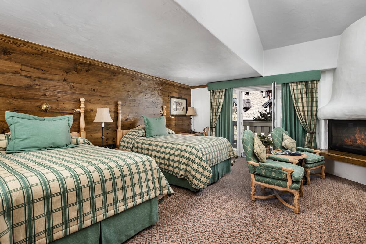 A hotel room with two beds, a fireplace, and a seating area with chairs and a table.