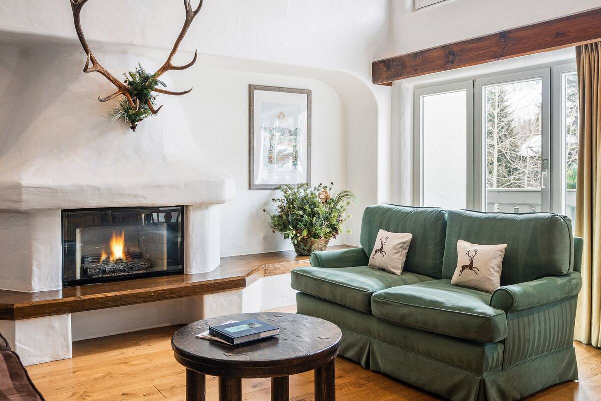 A cozy living room with a fireplace, a green sofa, and a coffee table.