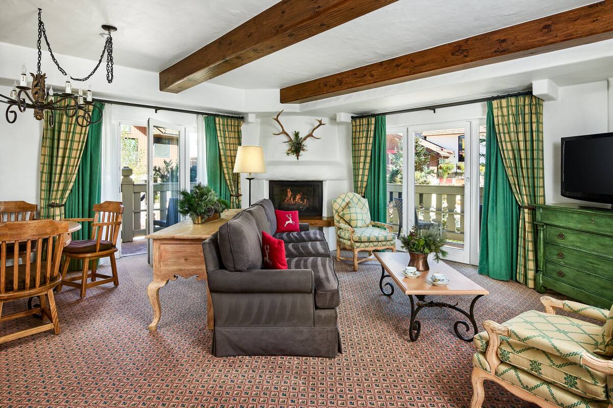 A cozy living room with a fireplace, wooden furniture, and green curtains.