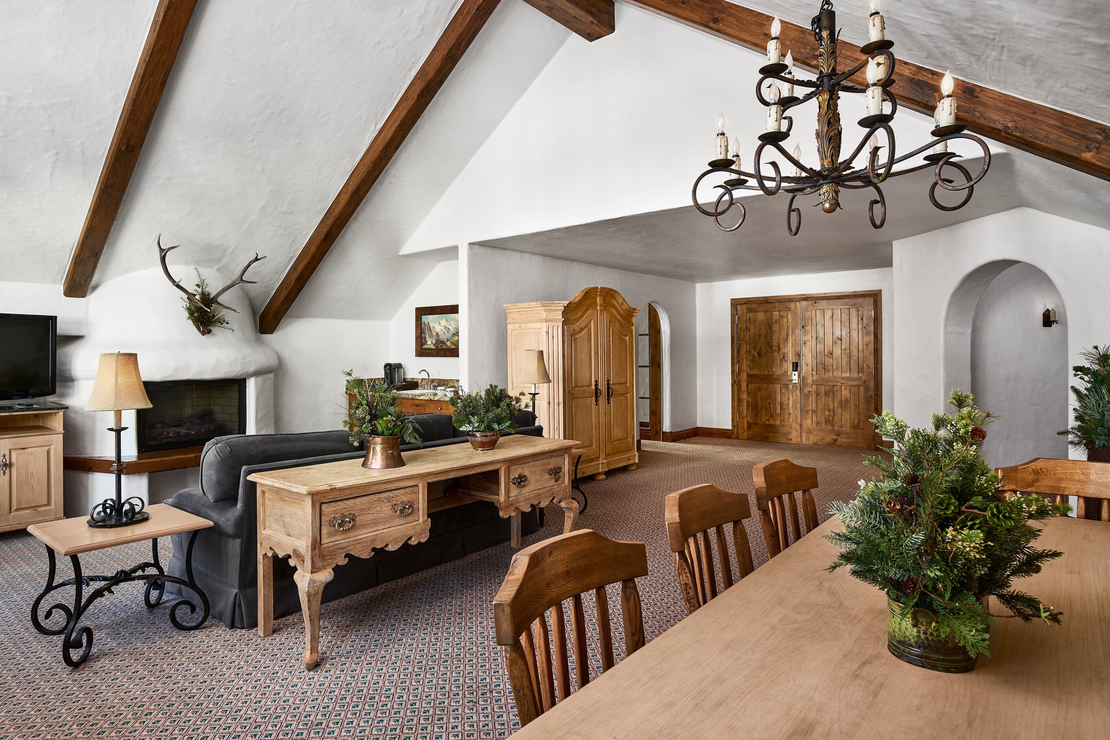 Een ruime loft met zichtbare houten balken, een open haard, een eethoek en een gezellige zithoek.