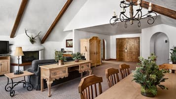 Een ruime loft met zichtbare houten balken, een open haard, een eethoek en een gezellige zithoek.