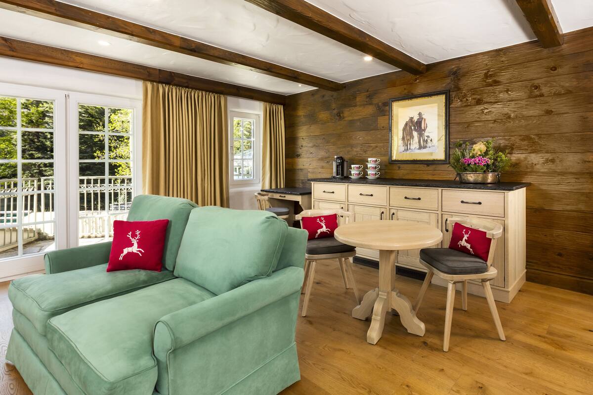 A cozy room with a green sofa, a small round table, and a wooden cabinet.