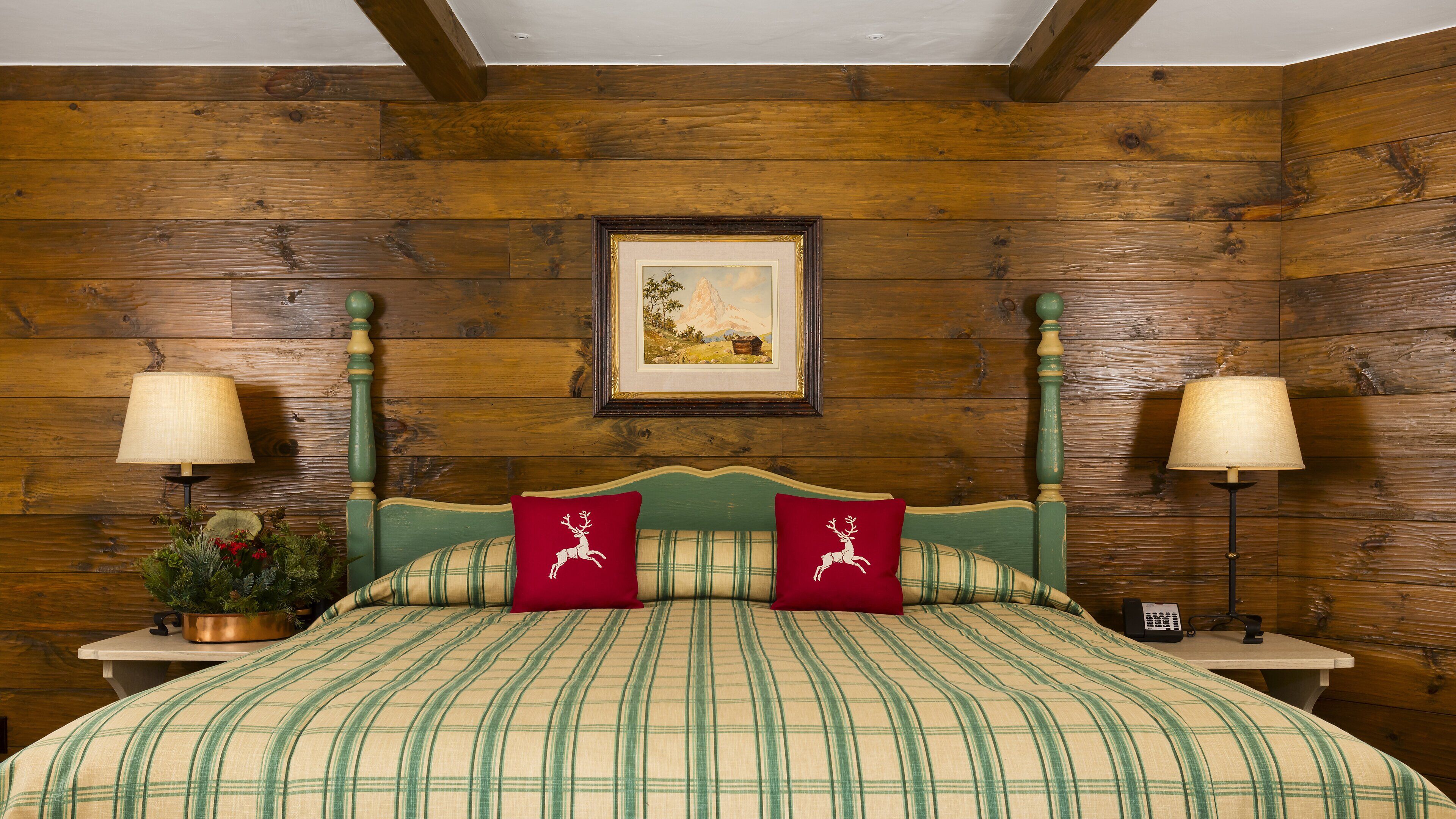 A wooden-paneled room with a bed, two nightstands, and two lamps.