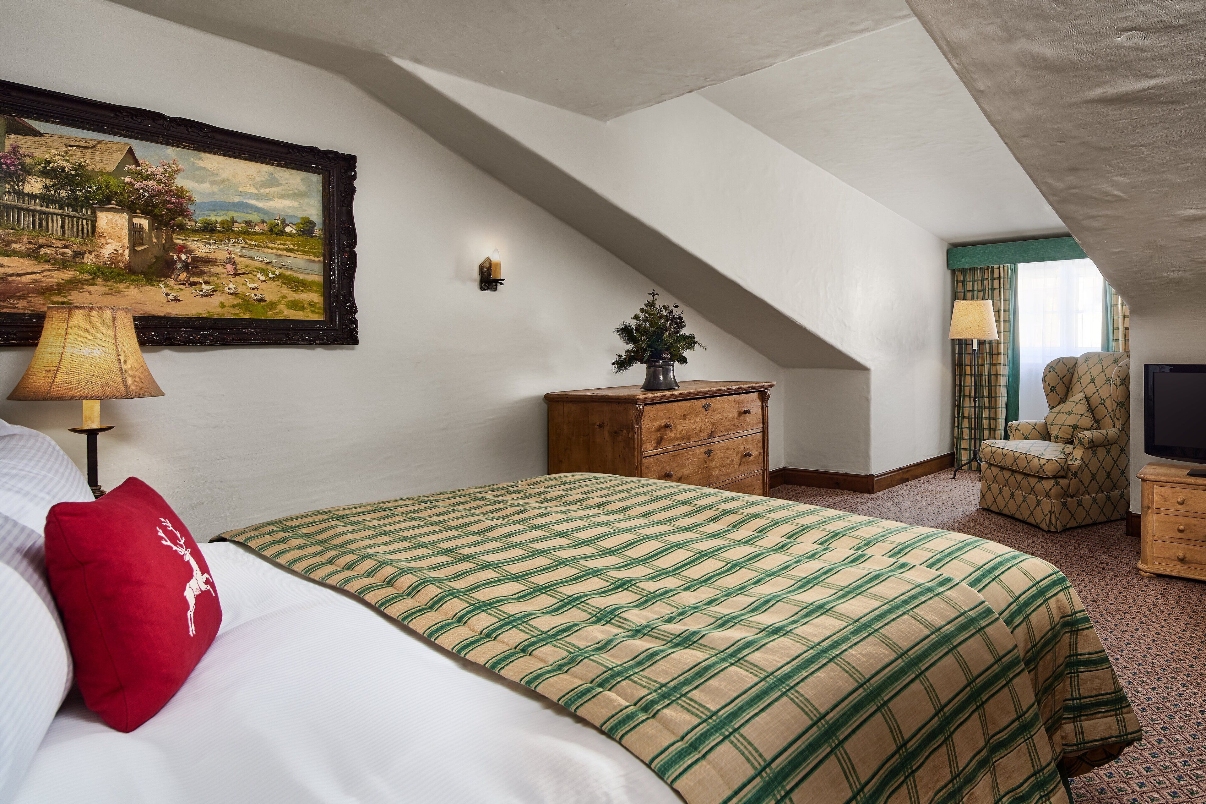 A bedroom with a bed, a dresser, a chair, a television, and a painting on the wall.