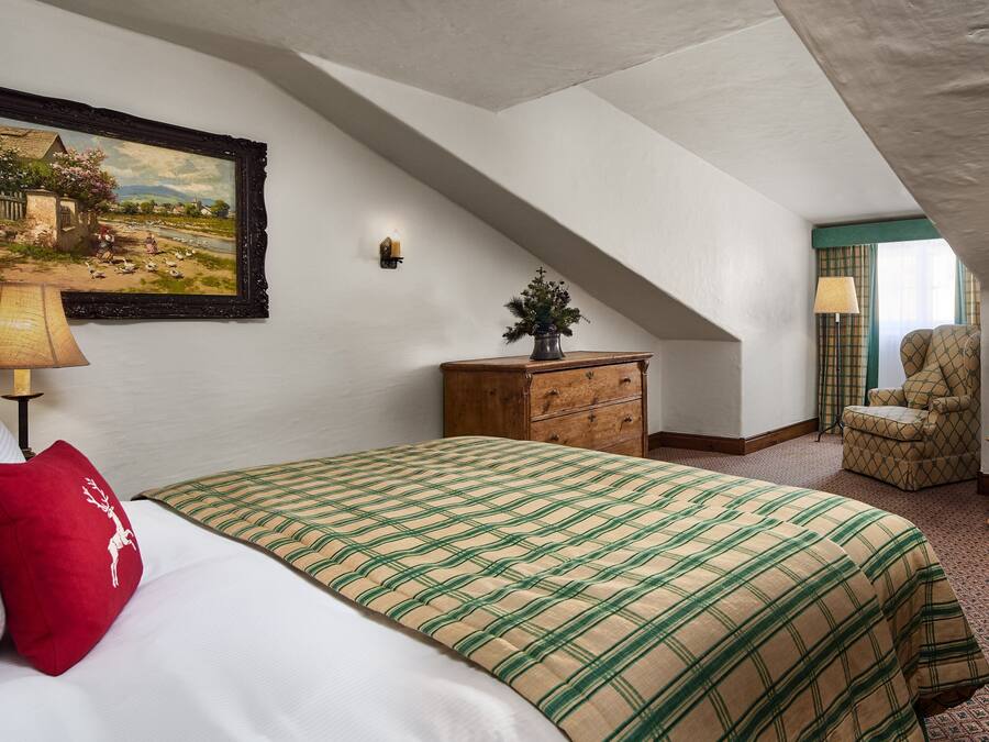 A bedroom with a bed, a dresser, a chair, a television, and a painting on the wall.
