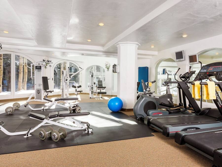 A well-equipped gym with cardio machines, weightlifting equipment, and a blue exercise ball.
