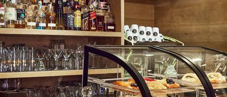 Una vitrina de panadería con pasteles y una variedad de botellas de licor al fondo.
