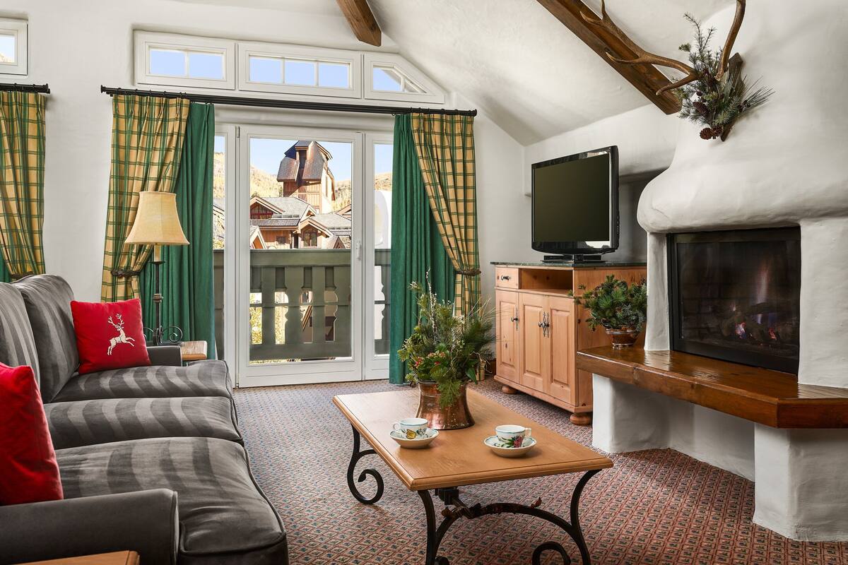 A cozy living room with a sofa, a coffee table, a fireplace, and a television.