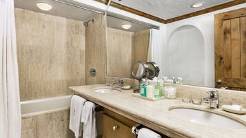 A bathroom with two sinks, a shower, and a large mirror.