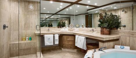 A modern bathroom with a glass shower enclosure, a large vanity with a bathtub, and a mirror with a decorative plant.