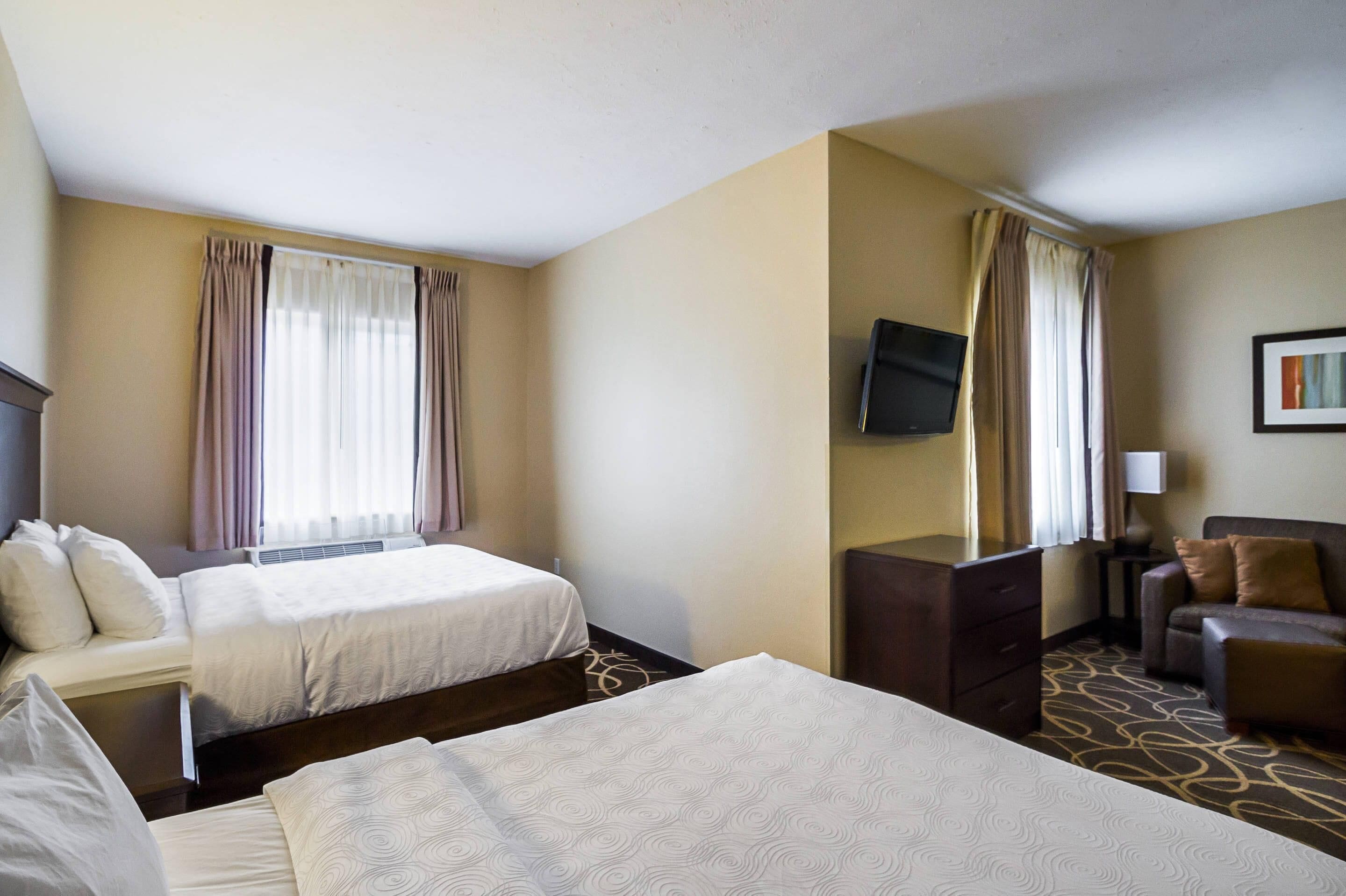 Een hotelkamer met twee bedden, een televisie, een bureau, een stoel en een bank.