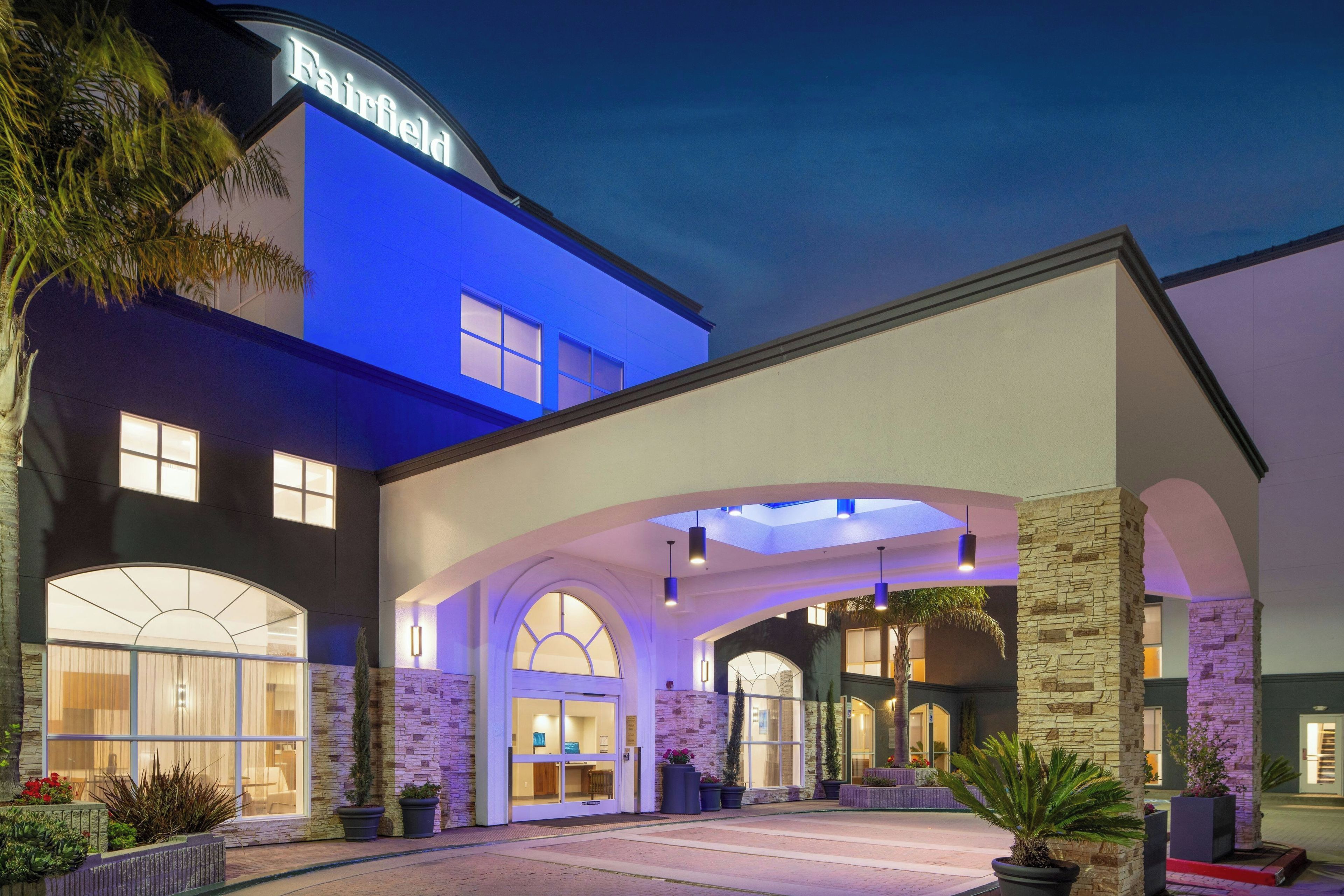 A hotel with a modern facade, large arched entrance, and a sign that reads 'Fairfield.'