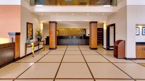 A spacious lobby with a reception desk, a seating area, and a staircase leading to an upper level. - Fairfield Inn & Suites by Marriott San Francisco Airport (Millbrae)