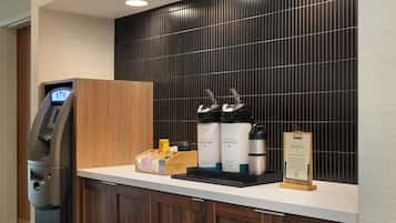 Zona de recepción de un hotel con un cajero automático, una máquina de café y un dispensador de agua.