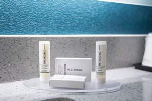 En badeværelsesbordplade med en Paul Mitchell shampoo, conditioner og en æske hårprodukter.