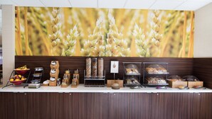 Un buffet proposant une variété de plats, avec en arrière-plan une grande fresque murale sur le thème du blé.