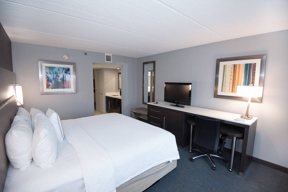 Een hotelkamer met een bed, bureau en televisie.