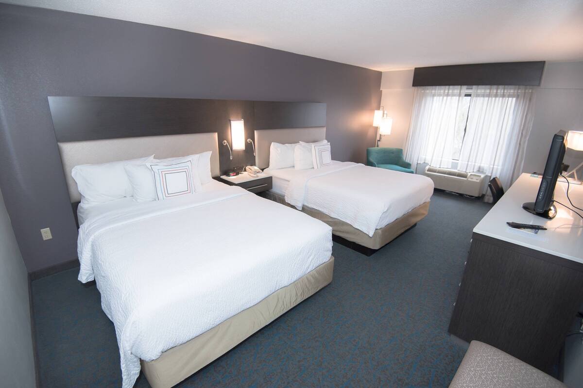 Een hotelkamer met twee bedden, een bureau en een stoel.