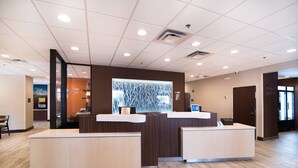 Un espace d’accueil au design moderne, comprenant un comptoir de réception, un coin salon et un mur décoratif.