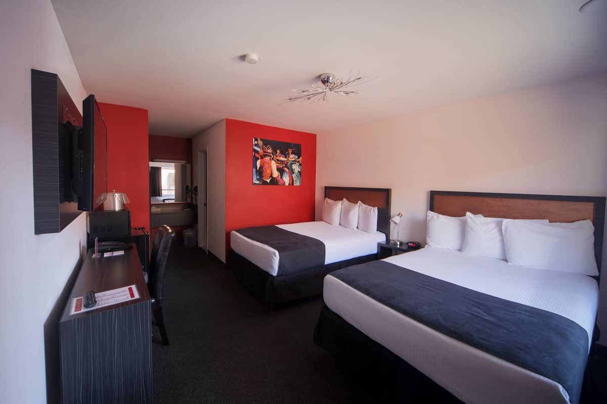 A hotel room with two beds, a desk, a chair, a television, and a painting on the wall.