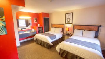 A hotel room with two beds, a bathroom with a mirror, and a painting on the wall.