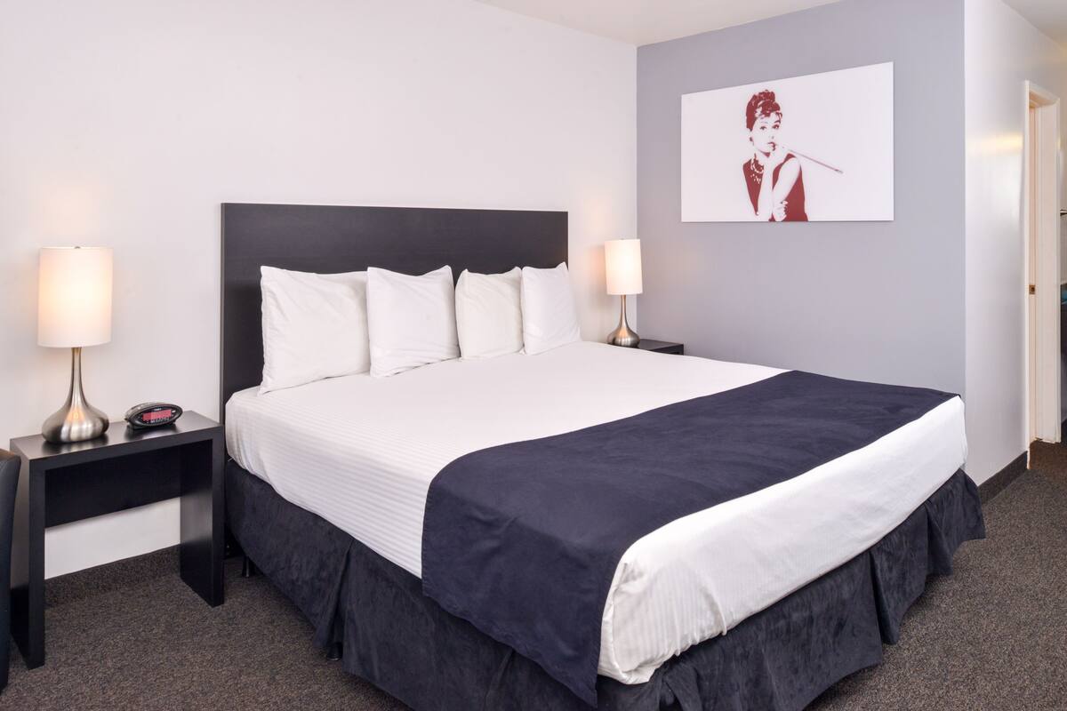 A hotel room with a large bed, two bedside tables, and a wall-mounted artwork.