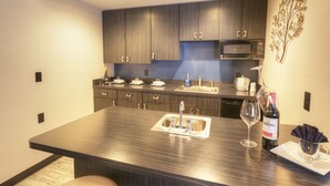 A modern kitchen with dark wood cabinets, a stainless steel sink, and a microwave. - Hotel Ruby (Spokane)