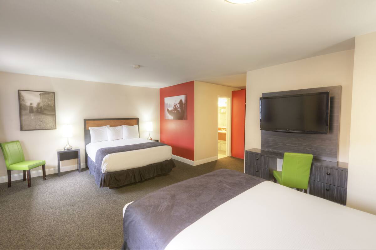 A hotel room with a large bed, a desk, a chair, a TV, and a painting on the wall.