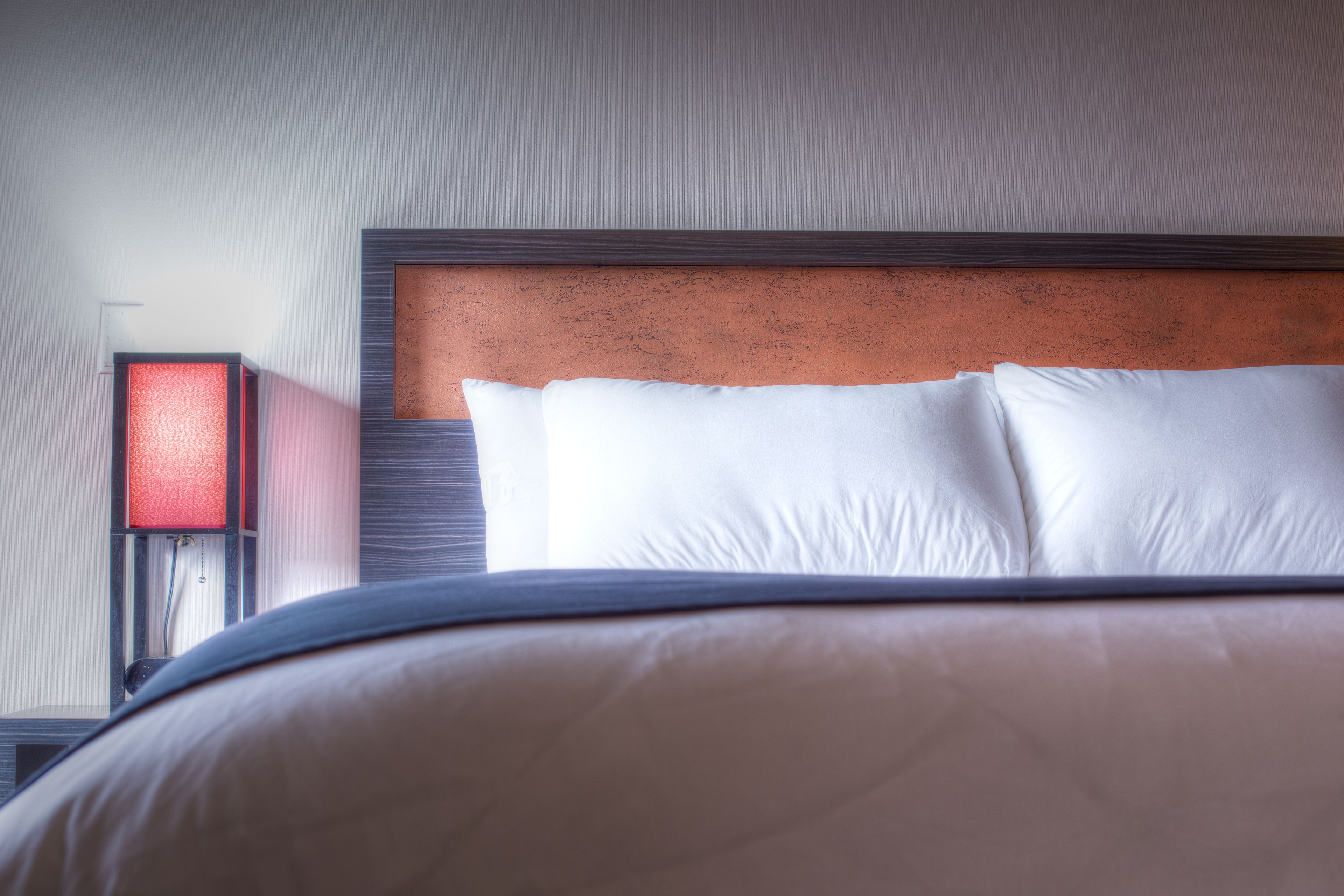 A neatly made bed with white pillows and a wooden headboard.