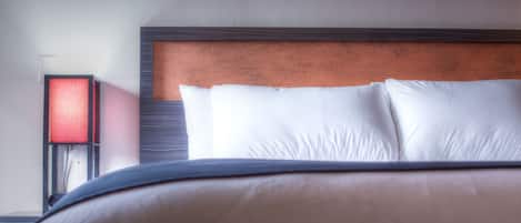 A neatly made bed with white pillows and a wooden headboard.