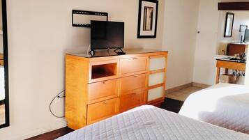 Une chambre d’hôtel avec deux lits, une commode en bois, un téléviseur et un tableau encadré au mur.