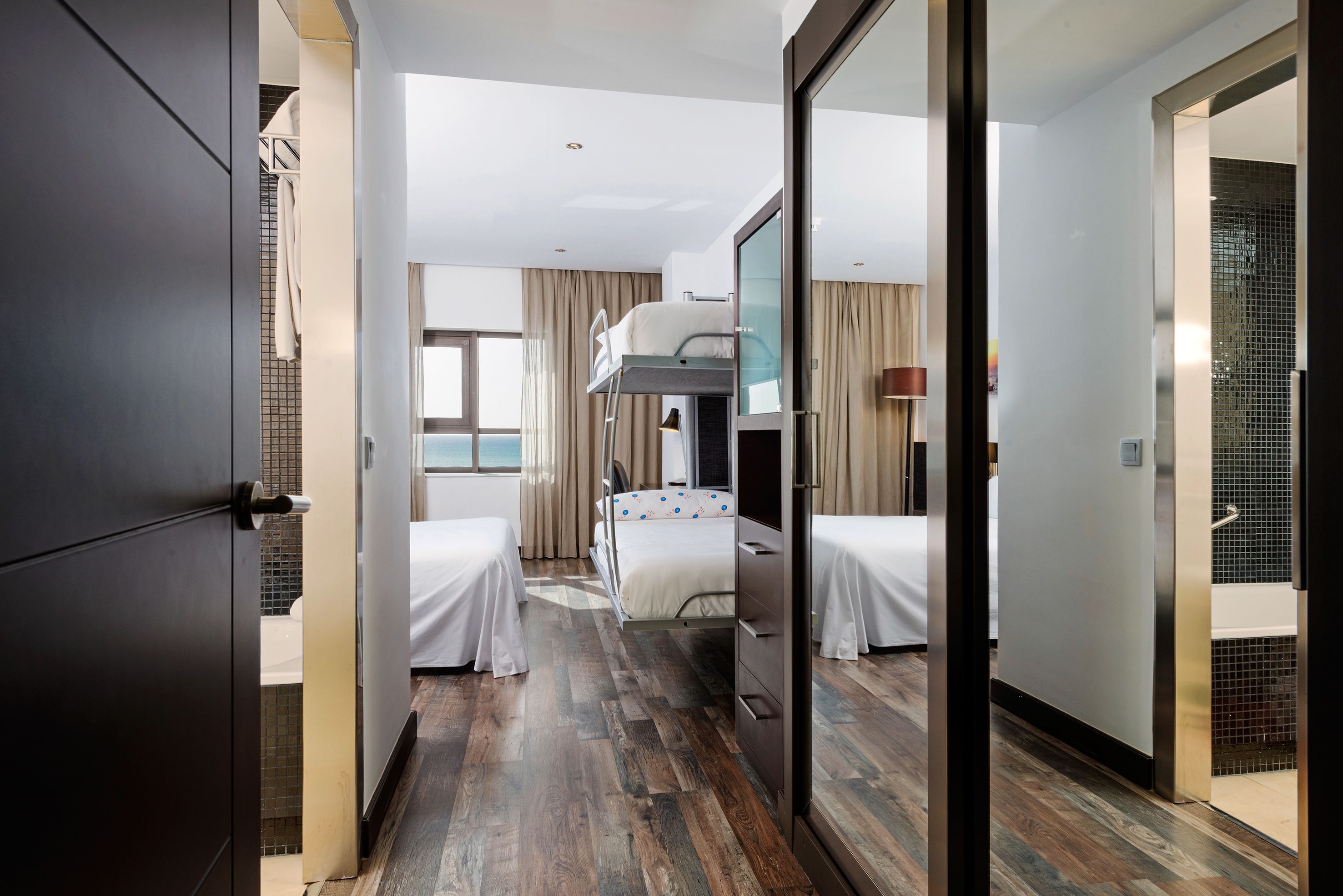 Habitación de hotel con literas, un escritorio y vista al mar.