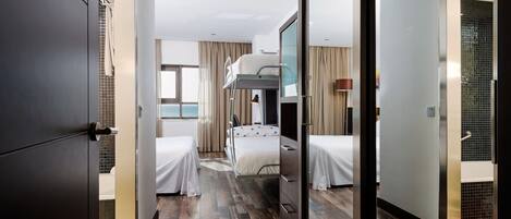 Habitación de hotel con literas, un escritorio y vista al mar.