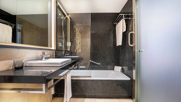 A modern bathroom with a large mirror, two sinks, a bathtub, and a glass shower enclosure.
