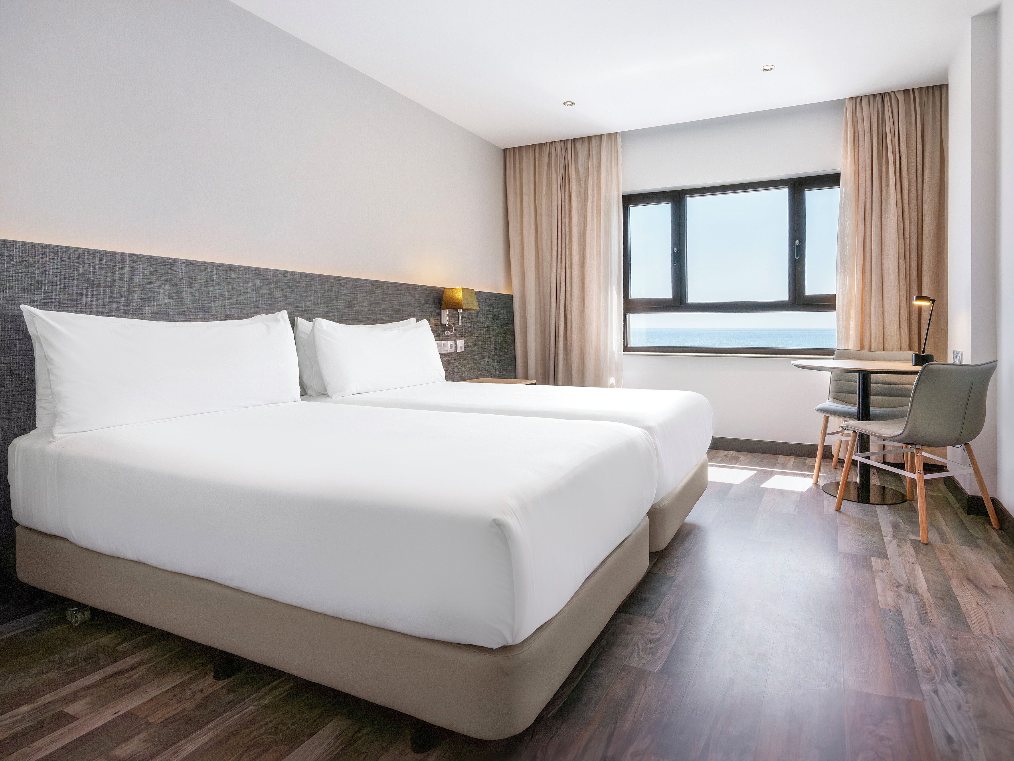 Una habitación de hotel con una cama grande, un escritorio y vista al mar.