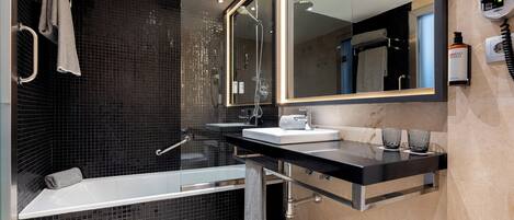 A modern bathroom with a glass-enclosed shower, a vanity with a sink, and a large mirror.