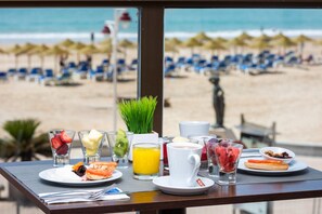 Enjoy a beachside breakfast with ocean views, featuring a selection of beverages and fresh pastries.