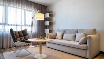 A modern living room with a sofa, a chair, a lamp, and a bookshelf.