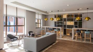 Un interior moderno con sofá, sillas, zona de comedor e iluminación colgante.
