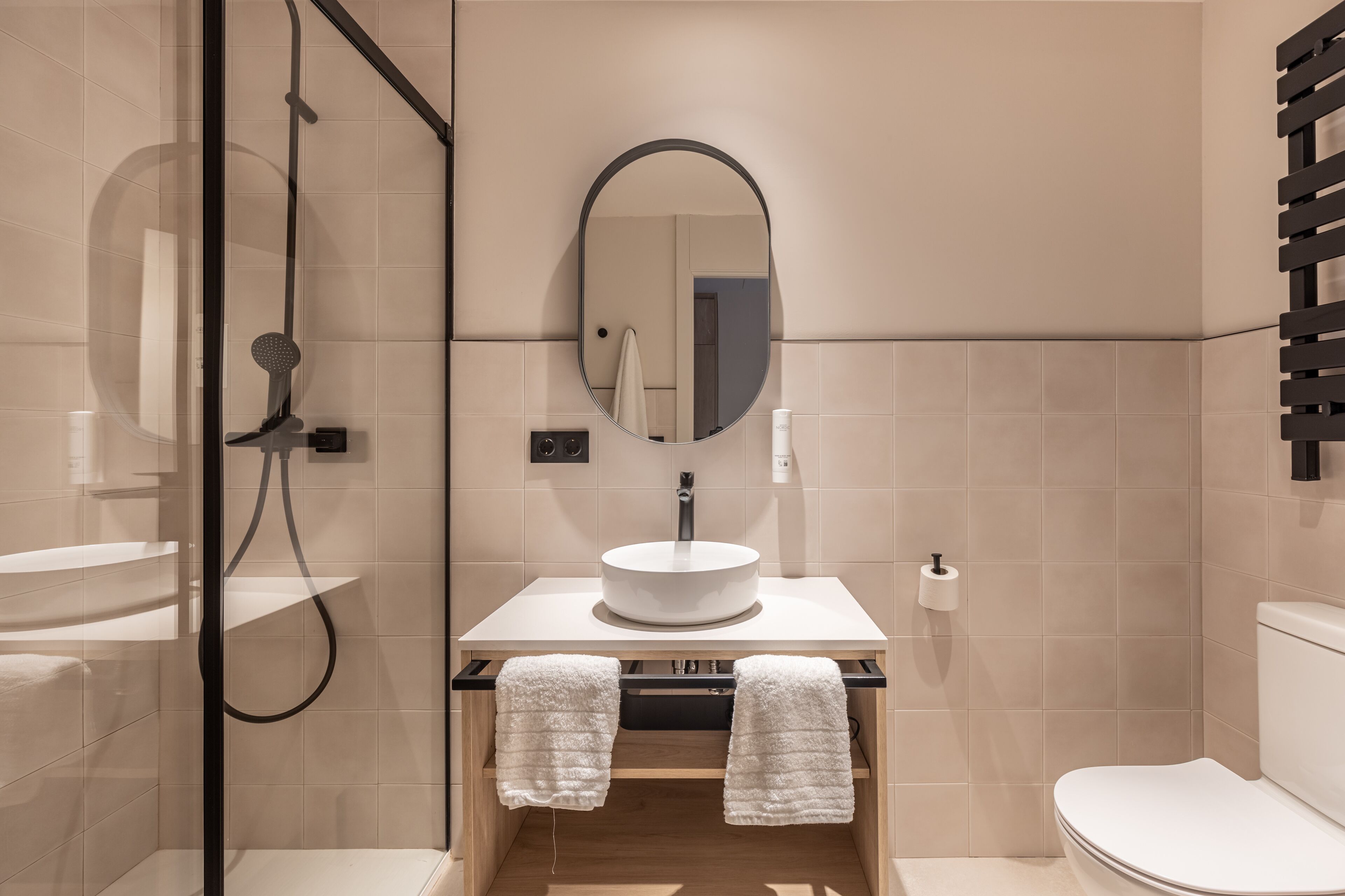A modern bathroom with a glass-enclosed shower, a round sink, and a toilet.