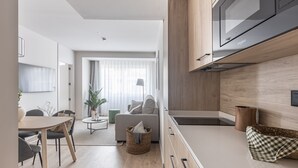 A modern kitchen with wooden cabinets, a built-in microwave, and a dining area with a table and chairs. - Líbere Madrid Chamberí (Madrid)