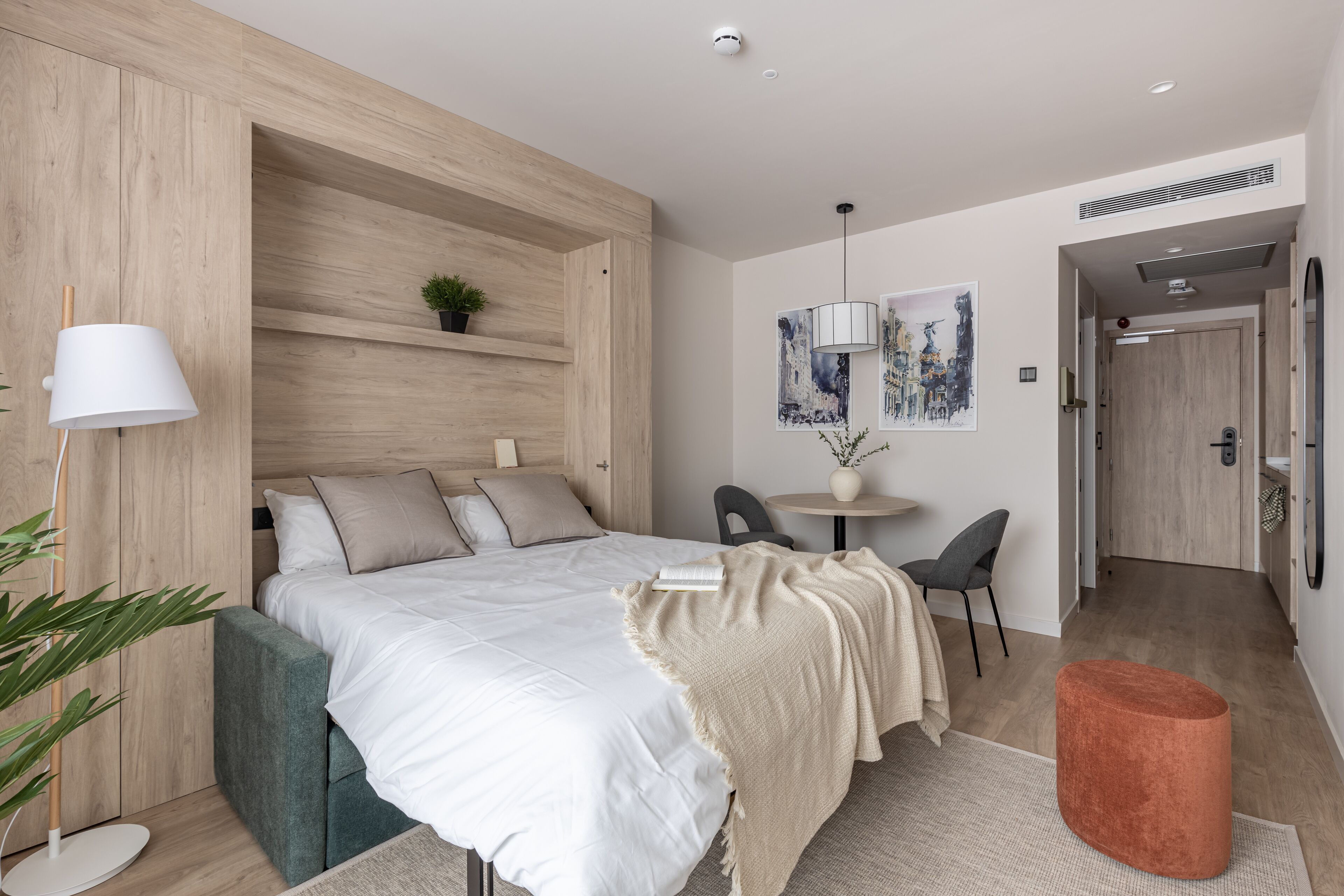 Ein modernes Schlafzimmer mit Bett, Nachttisch, Lampe und einem kleinen Topfpflanzen.