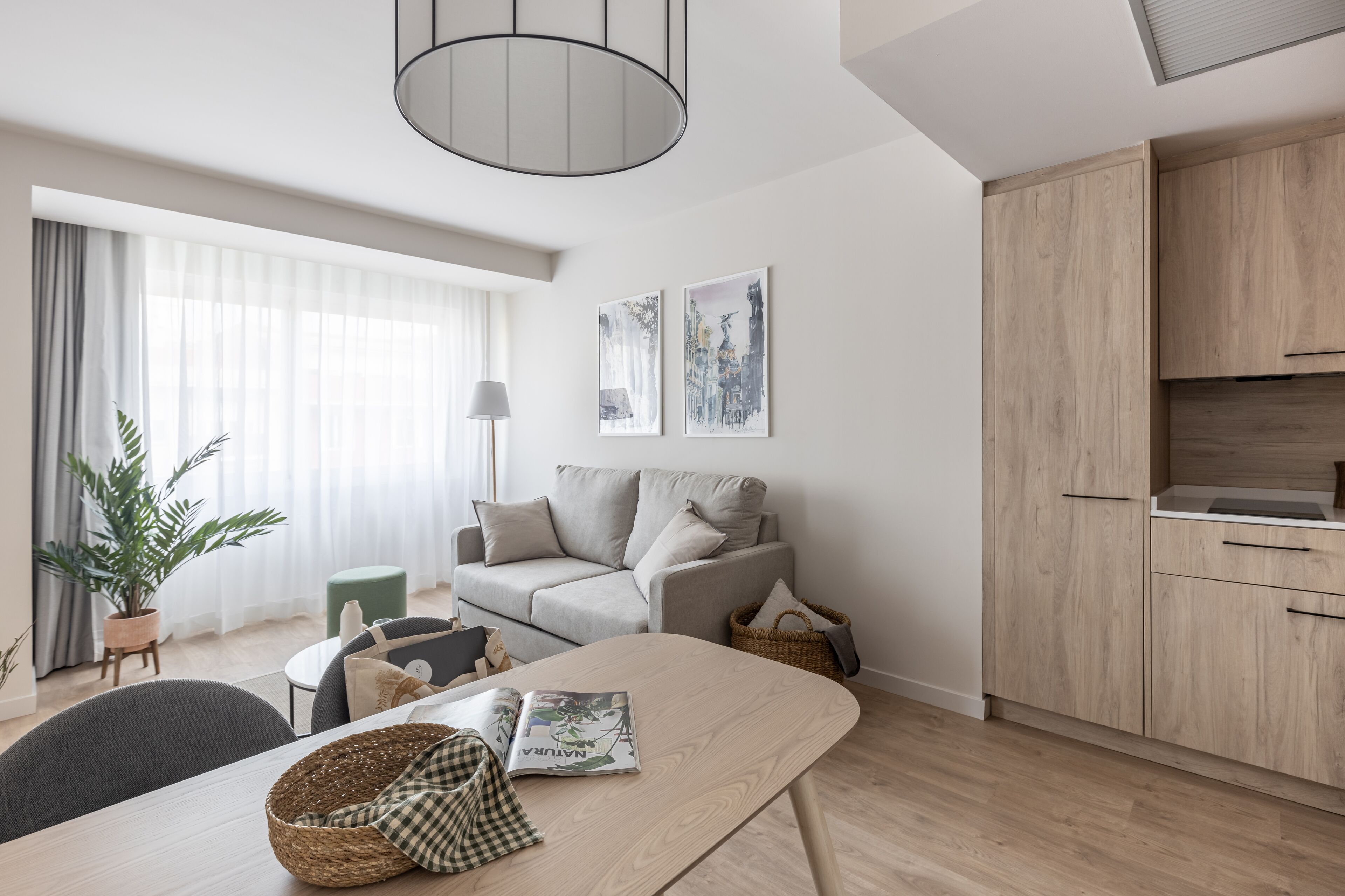 A modern living space with a sofa, dining table, and kitchen area.