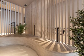 A modern interior with vertical wooden slats, a curved wooden bench, and a small plant. - Líbere Madrid Chamberí (Madrid)